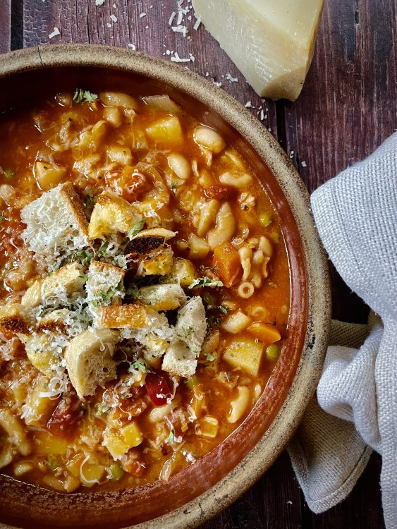 A bowl of homemade minestrone soup, served with grated parmesan and croutons.